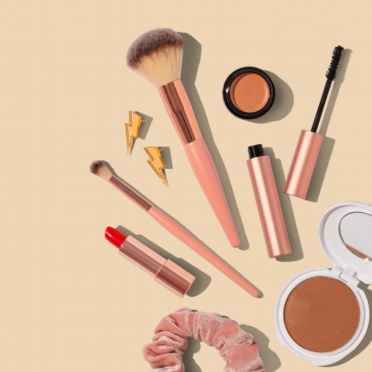 A compact, a lip gloss and a mascara on stone